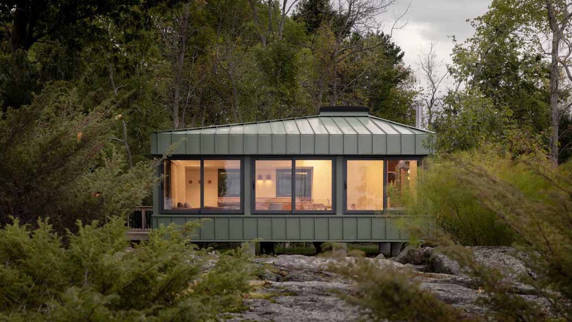 green-metal-siding-allows-this-small-cottage-to-blend-in-with-its-surroundings