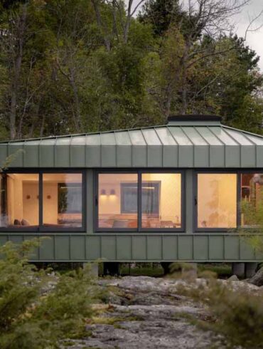 green-metal-siding-allows-this-small-cottage-to-blend-in-with-its-surroundings