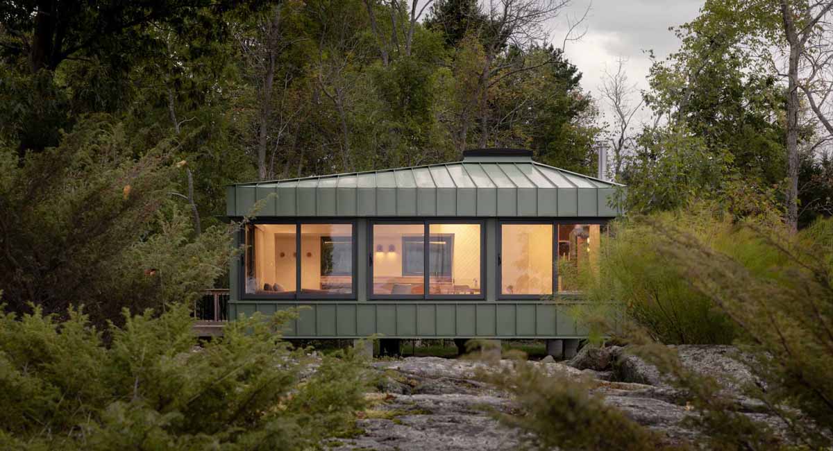 green-metal-siding-allows-this-small-cottage-to-blend-in-with-its-surroundings