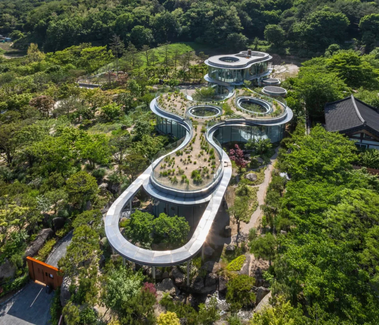 MIGIUI cafe with a green roof and curved glass walls in the hanok village of Ulju-gun, South Korea