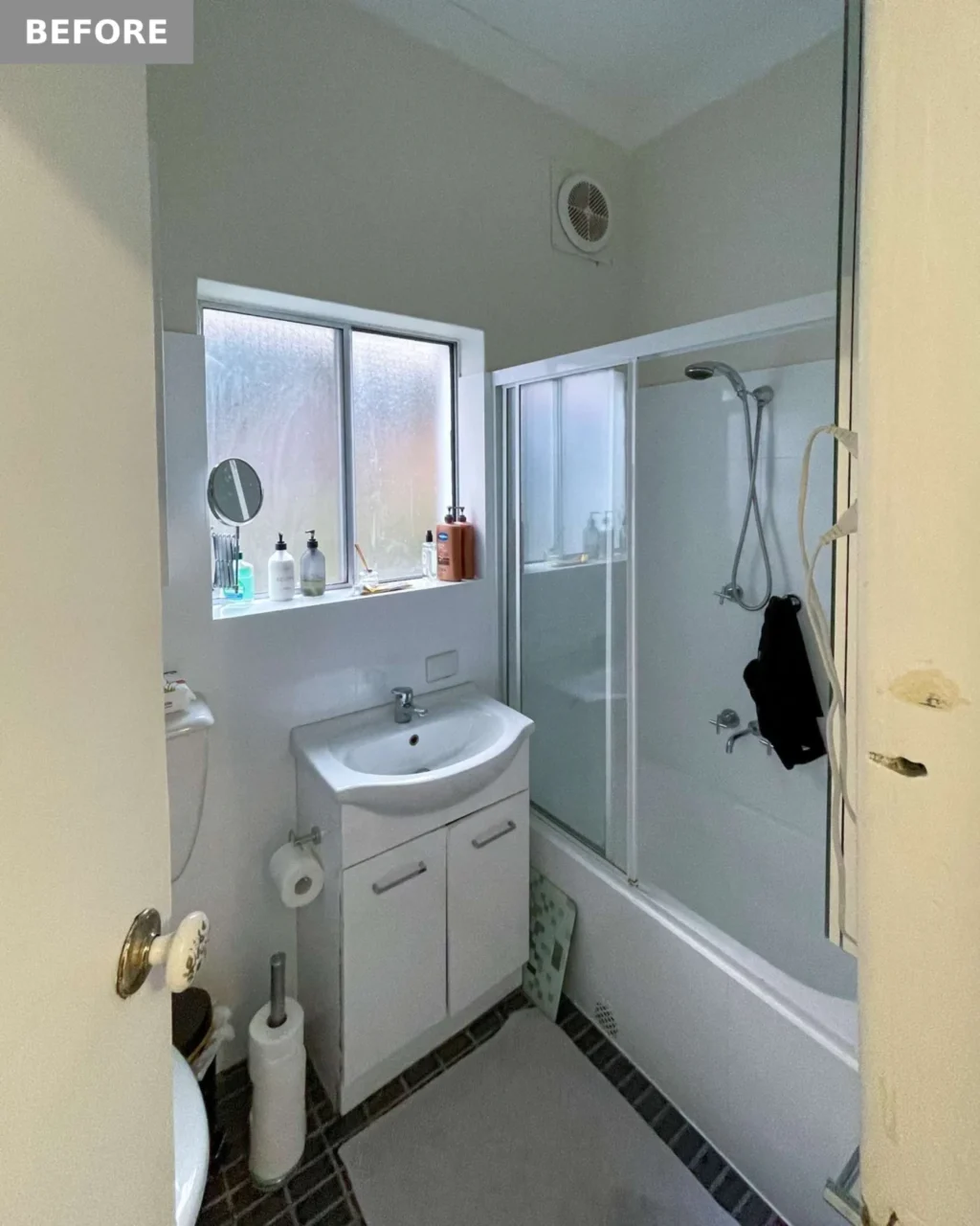 Before: the original bathroom with dark floor tiles and a shower over the bath