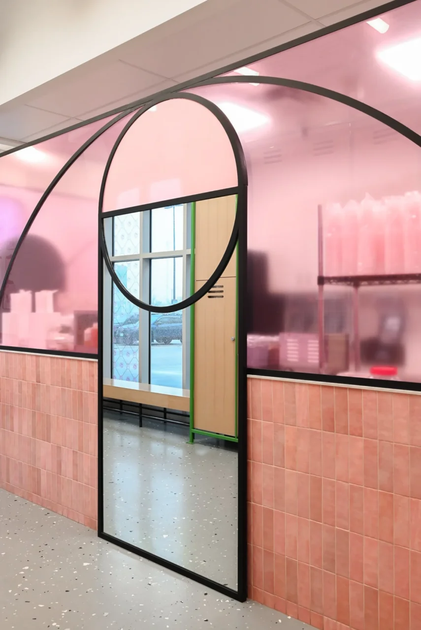 Curved black frames, pink and white tile and a full-length mirror inside the shop