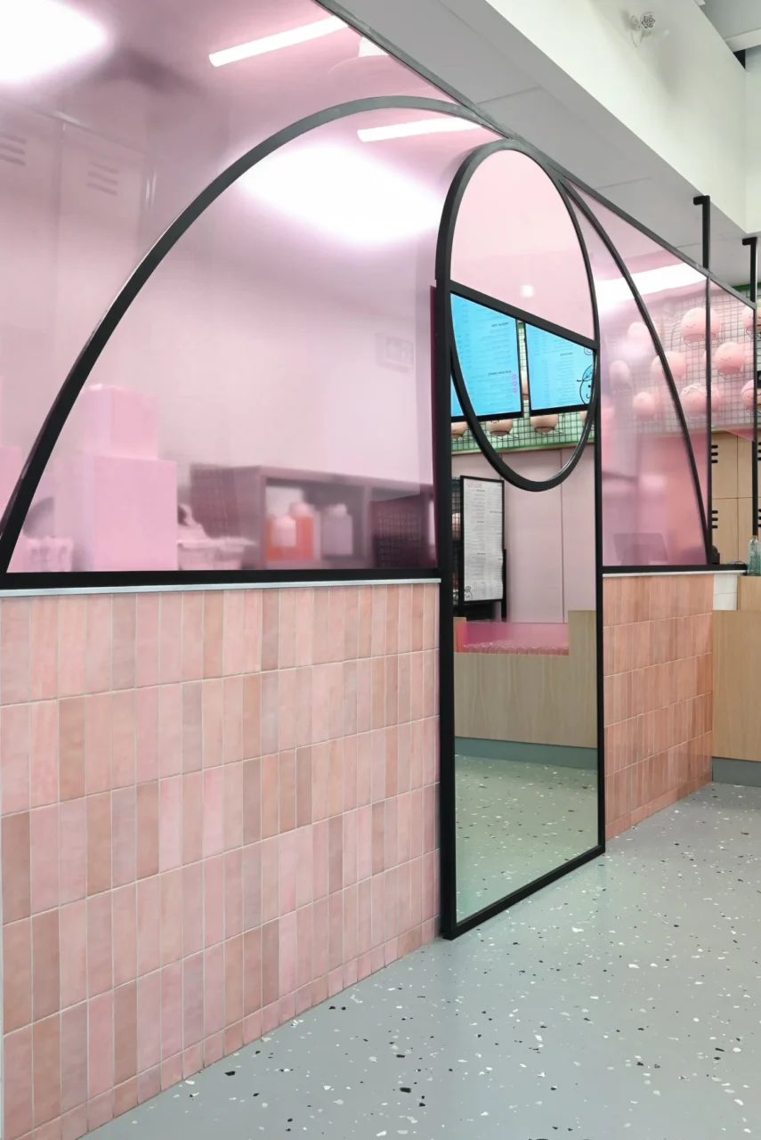 Mirror and pink tile in the shop extending the view of the compact interior