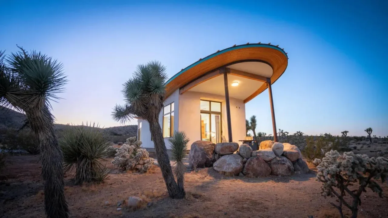Strawbale desert cabin with a butterfly roof, covered in natural lime plaster