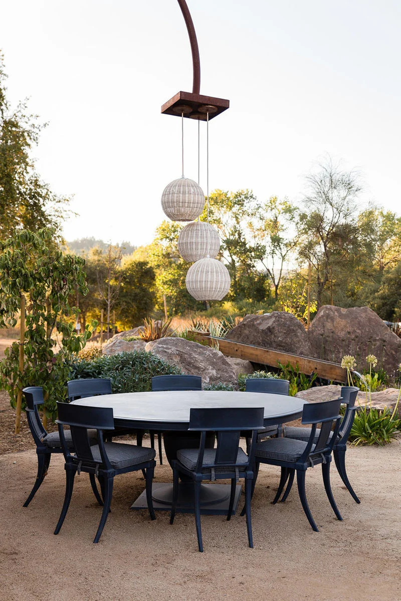 Round outdoor dining table among rock landscaping by landscape designer Jake Moss