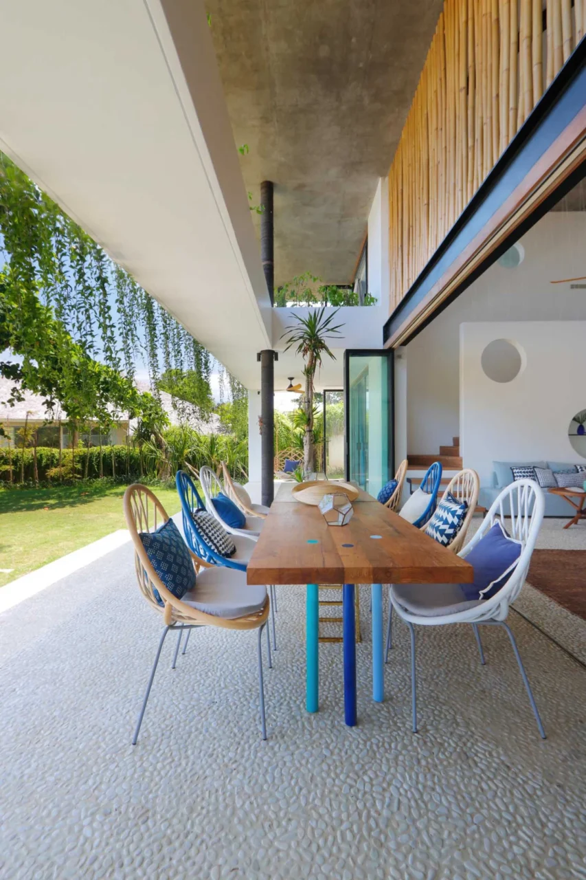Covered outdoor dining area with a solid wood table and colourful chairs, Word Of Mouth House