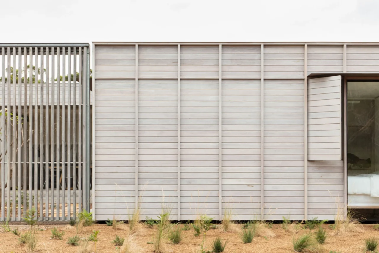Pale timber cladding and a hinged shutter beside a narrow window and a larger glass pane