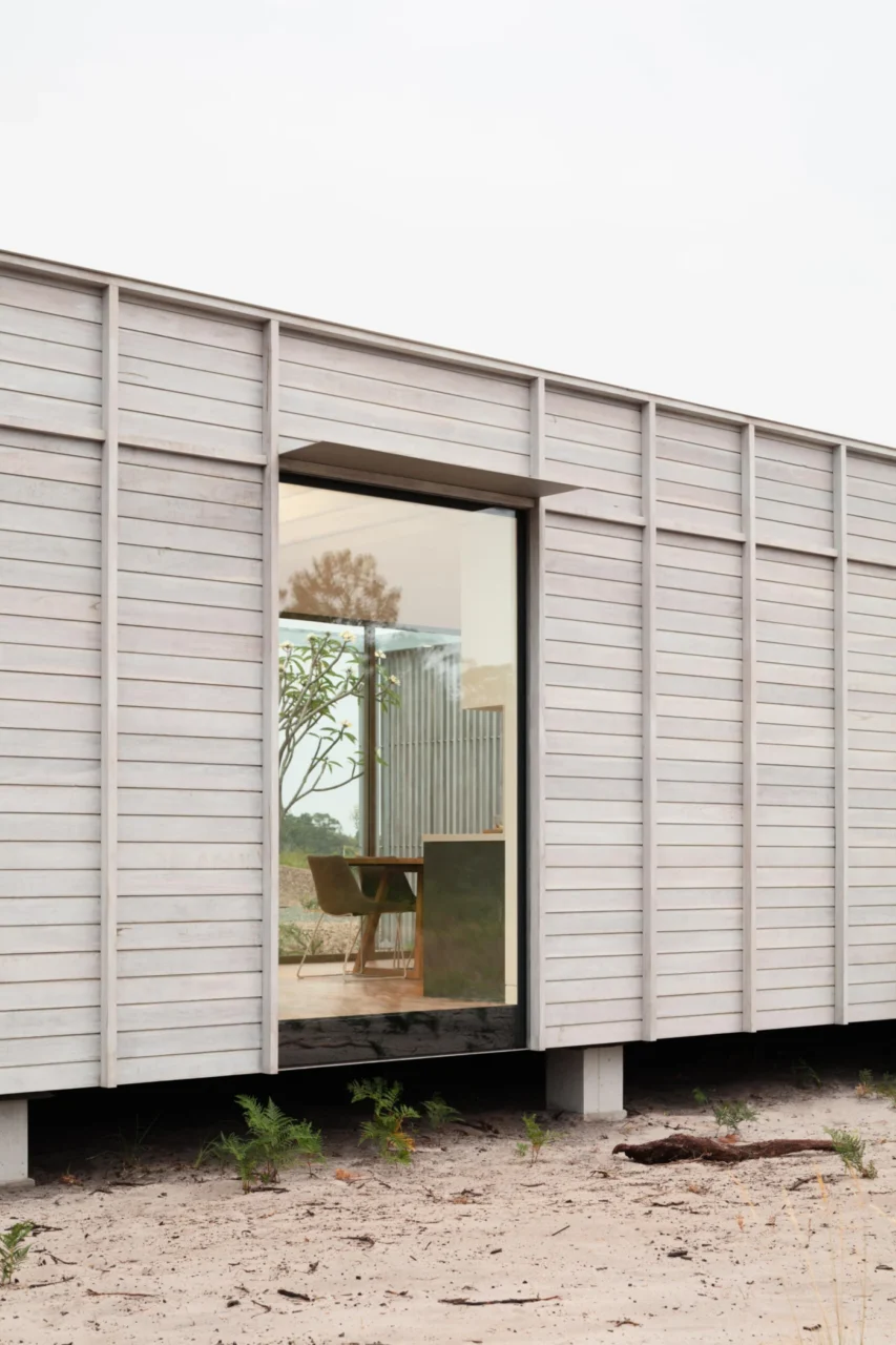 Picture window showing a dining table and chair inside the prefab home