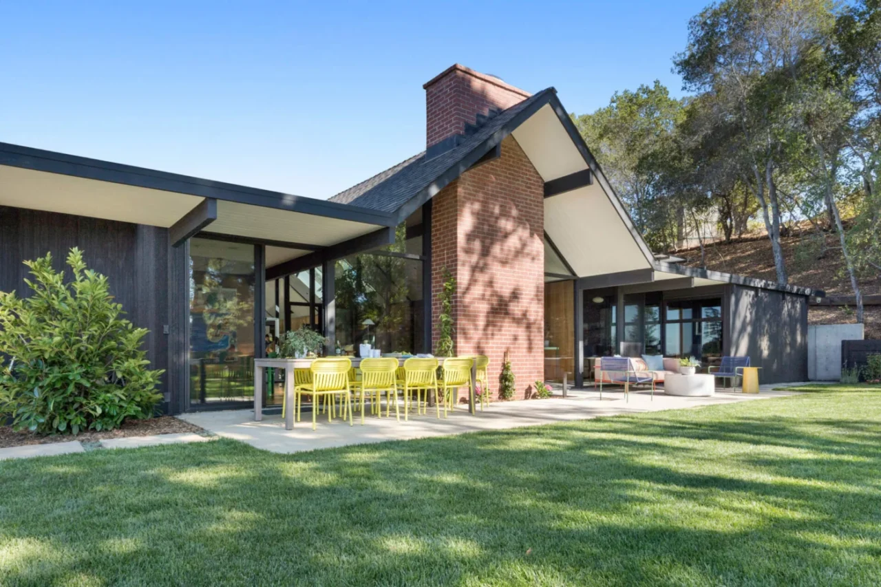 Gabled roof flanked by two flat-roofed wings of the mid-century house