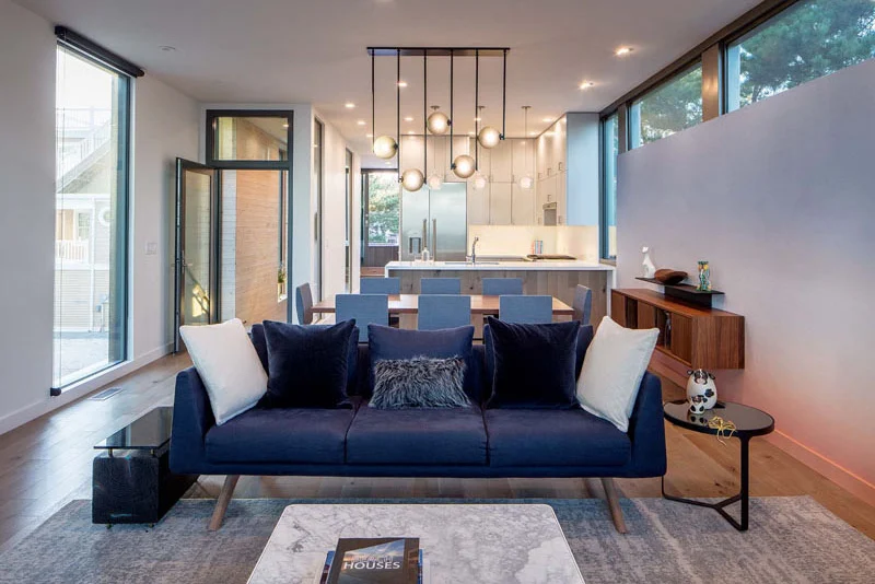 Open living, dining and kitchen area in a beach house in New Jersey by Specht Novak
