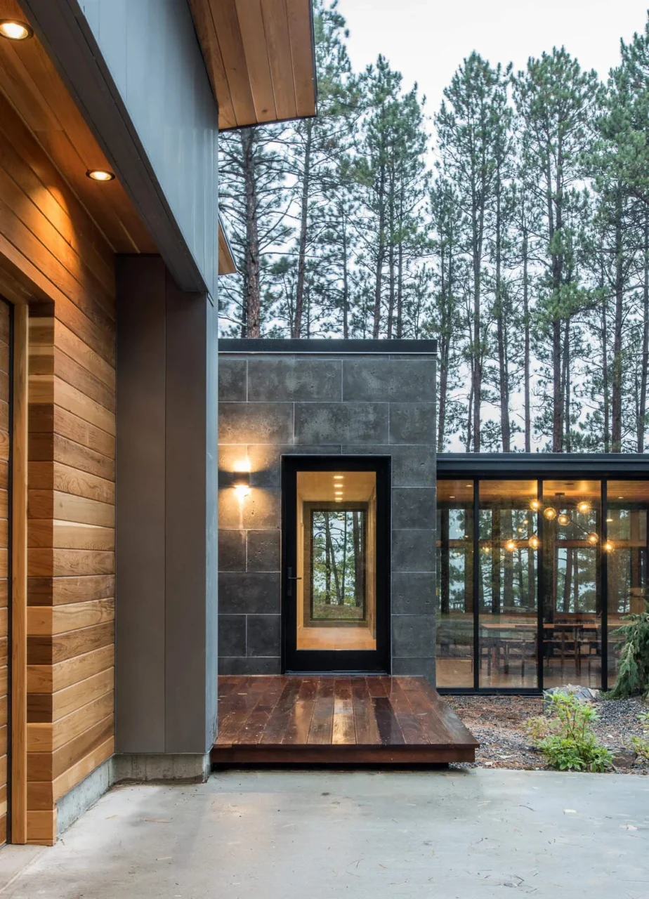 Glass front door set in stone and wood at the entrance of the lake house