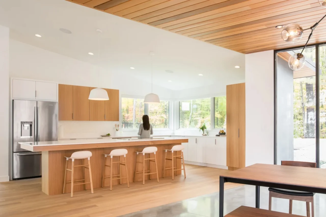 Kitchen with white oak cabinets, white walls and large windows onto the trees