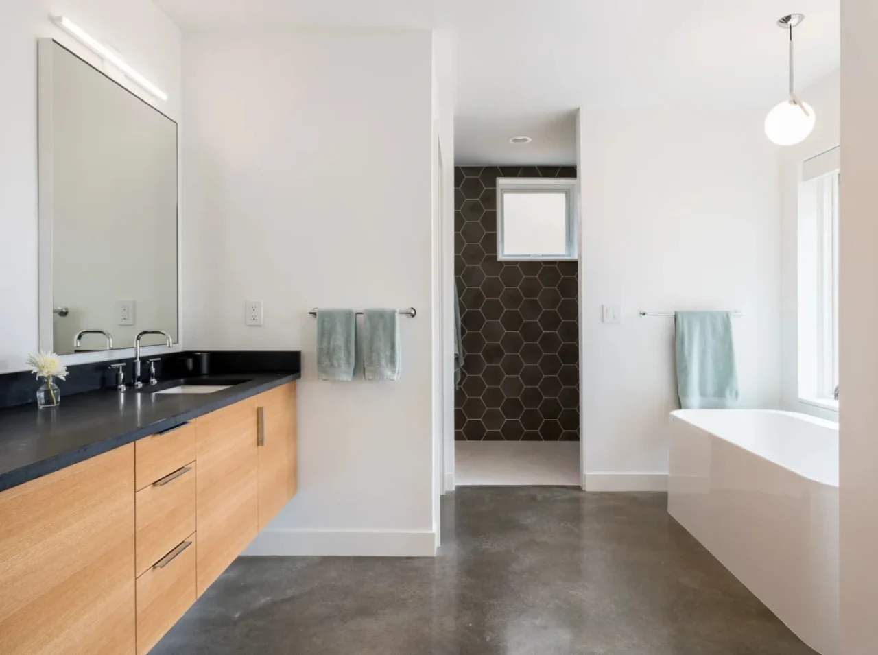 Main bathroom with dark grey hexagonal tiles, concrete floor and wood vanity