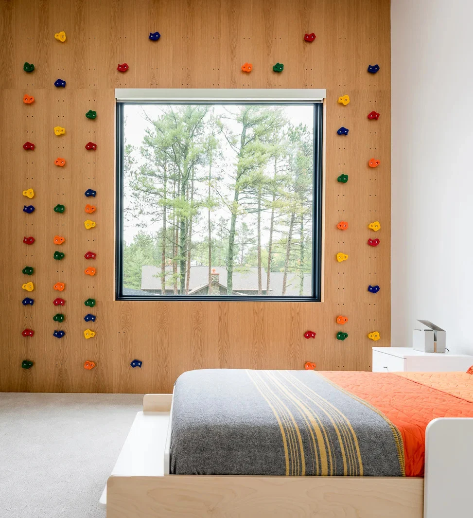 Kids bedroom with a climbing wall wrapped around the window
